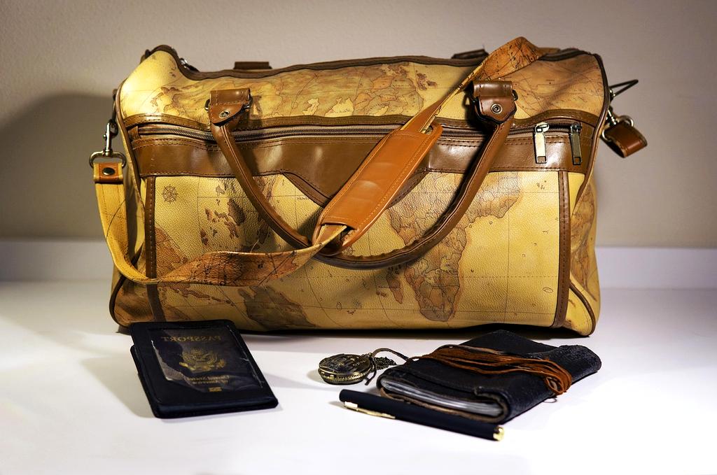 Open travel journal and map on wooden table with compass and camera